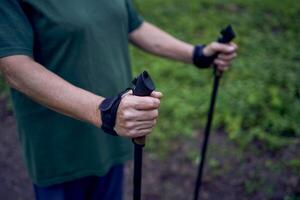 anziano donna è impegnato nel nordico a piedi con bastoni nel il primavera foresta foto