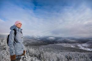 giovane donna che guarda il panorama dalla cima di una montagna in inverno
