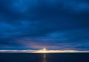 tramonto sull'oceano in una sera nuvolosa scura foto