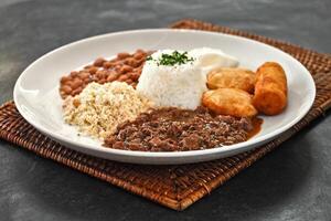 Manzo tritare con Riso, fagioli, fritte uovo, Pasticcino, farofa e impanato Banana foto