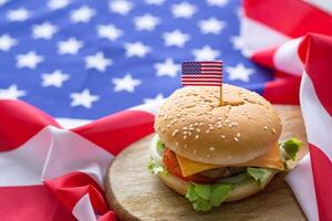 avvicinamento di fatti in casa Due Hamburger con lattuga e formaggio ha un americano bandiera perno su il Hamburger posto su un' di legno chopping tavola con un americano bandiera sfondo su un' di legno tavolo foto
