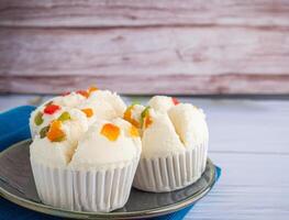 lato Visualizza di tailandese al vapore cupcakes sormontato con asciutto frutta su un' piatto su un' blu stoffa posto su un' di legno sfondo. khanom pui fai nel tailandese. spazio per testo foto