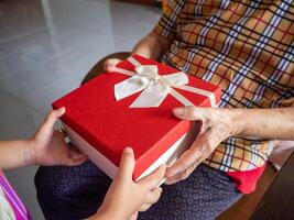 avvicinamento di un' donna mano dando un' regalo scatola per un' anziano donna. concetto di vacanza e Festival foto