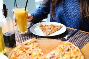 persona seduta a tavolo con piatto di Pizza e bicchiere di arancia succo foto