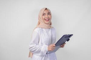 sorridente giovane asiatico musulmano donna indossare bianca vestito e hijab Tenere un' documento, isolato di bianca sfondo. Ramadan e eid mubarak concetto foto