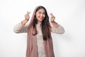 un' contento giovane asiatico musulmano donna indossare velo hijab fabbricazione amore cuore forma utilizzando mani su isolato bianca sfondo. Ramadan e eid mubarak concetto foto