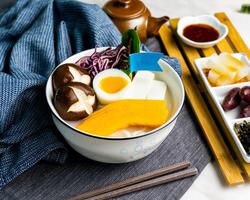 pesce udon nel di spessore pesce la minestra servito nel ciotola con bastoncini e guarnizione bandiera isolato su tovagliolo lato Visualizza di giapponese cibo su tavolo foto