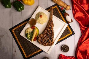 firma tomahawk osso bistecca con nero Pepe, salsa e insalata servito nel piatto isolato su tovagliolo avvicinamento superiore Visualizza su di legno tavolo italiano cibo foto