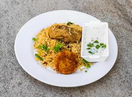 pollo biryani o pulao con shami kabab tikki e menta raita servito nel piatto isolato su sfondo superiore Visualizza di indiano spezie e pakistano cibo foto