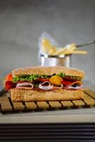 Ciabatta affumicato prosciutto Sandwich isolato su di legno con Maionese tuffo e francese patatine fritte secchio tavola lato Visualizza di italiano veloce cibo su grigio sfondo foto