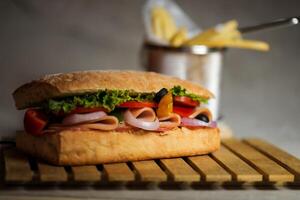 Ciabatta affumicato prosciutto Sandwich isolato su di legno con Maionese tuffo e francese patatine fritte secchio tavola lato Visualizza di italiano veloce cibo su grigio sfondo foto