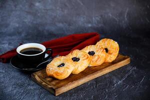 mirtillo crema pasticciera danese servito su di legno tavola con tazza di nero caffè isolato su tovagliolo lato Visualizza di francese prima colazione al forno cibo articolo su grigio sfondo foto