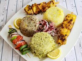 pollo joojeh kebab riso con cipolla, Limone servito nel piatto isolato su tavolo avvicinamento superiore gareggiare di Arabo speziato cibo foto