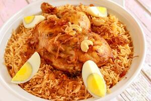 Arabia pollo kabsa pulao riso con fritte cipolla, anacardio Noce e bollito uovo servito nel pentola piatto isolato su di legno tavolo superiore Visualizza Arabo speziato cibo foto