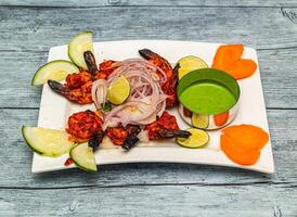 zafferano grigliato gamberetto o tandoori jhinga con Limone e cipolla servito nel piatto isolato su di legno tavolo superiore Visualizza di indiano speziato cibo foto