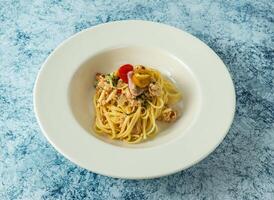 Granchio carne aglio olio con ciliegia pomodoro e Limone servito nel piatto isolato su sfondo superiore Visualizza di italiano cibo foto