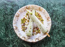 shahi kulfi o kulfi includere khoya, latte, pista, pistacchio con bastone servito nel piatto isolato su sfondo superiore Visualizza di pakistano e indiano ghiaccio crema foto