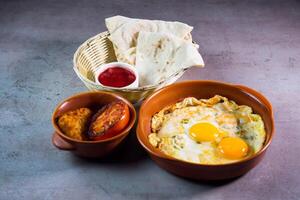 speziato uovo con pane, fritte pomodoro e salsa servito nel piatto isolato su grigio sfondo superiore Visualizza di bahrain cibo foto