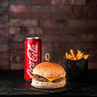 Manzo hamburger con patatine fritte secchio e Coca Cola può 250 ml servito nel piatto isolato su di legno tavolo lato Visualizza di Arabo Fast food foto