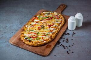 mediterraneo Pizza con nero Pepe servendo su di legno taglio tavola isolato su grigio sfondo superiore Visualizza di Fast food foto
