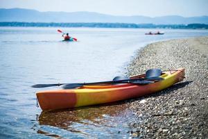 kayak in riva al mare con i canoisti sullo sfondo foto