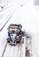 spazzaneve che rimuove la neve dall'autostrada durante una tempesta di neve foto