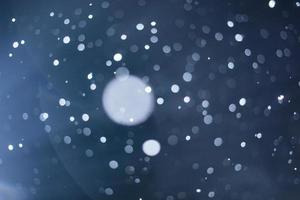 bagliore dell'obiettivo bagnato e trasandato e fiocchi di neve sfocati durante la tempesta di neve di notte foto