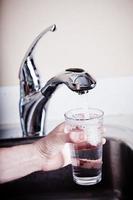 uomo assetato che riempie un grande bicchiere d'acqua foto