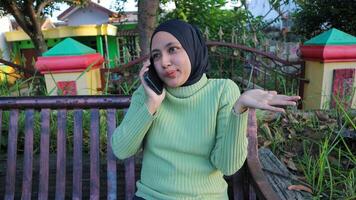 contento asiatico musulmano donna parlando su mobile Telefono nel parco, gratuito spazio foto