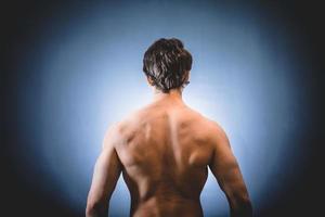 bodybuilder muscolare che mostra schiena e spalle