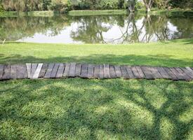 riga di di legno passerelle nel il giardino con un' stagno nel il sfondo foto