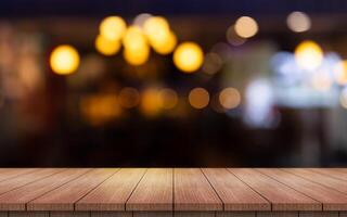 vuoto di legno tavolo superiore con luci bokeh su sfocatura ristorante sfondo. foto