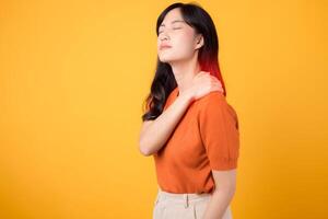 collo dolore terapia medico ufficio sindrome concetto. ha riguardato giovane asiatico donna nel sua anni '30, indossare un arancia camicia, detiene sua dolore spalla su giallo sfondo. foto