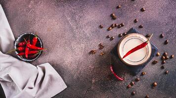 tazza di caldo speziato caffè latte macchiato con rosso chili Pepe su il tavolo superiore Visualizza ragnatela bandiera foto