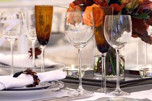 sofisticato tavoli con piatti, posate e bene bicchieri avvicinamento foto