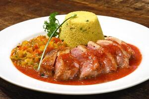 arrosto anatra con salsa e marocchino couscous su piatto foto