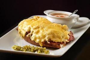 Aperto pastrami Sandwich su piatto con Gratinato formaggio e vinaigrette salsa foto