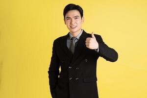 ritratto di asiatico maschio uomo d'affari. indossare un' completo da uomo e in posa su un' giallo sfondo foto