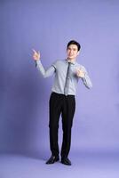 ritratto di asiatico maschio uomo d'affari in piedi e in posa su viola sfondo foto