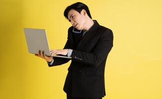 ritratto di asiatico maschio uomo d'affari. indossare un' completo da uomo e in posa su un' giallo sfondo foto