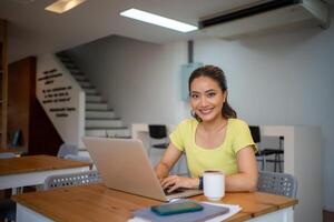 donna seduta Lavorando con il computer portatile a caffè negozio, libero professionista donna Lavorando al di fuori concetto. foto