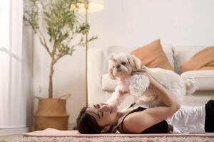 giovane donna nel abbigliamento sportivo fare meditazione pratica e yoga con carino cane nel vivente camera, salutare stile di vita, mentale Salute concetto. foto