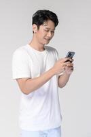 ritratto di giovane sorridente asiatico uomo utilizzando smartphone al di sopra di bianca sfondo foto