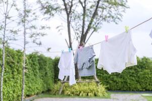 Abiti sospeso lavanderia su lavaggio linea per essiccazione contro blu cielo all'aperto foto