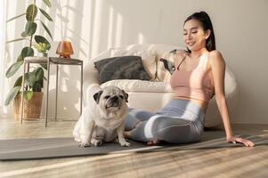 asiatico donna nel abbigliamento sportivo esercizio e fare yoga con carino cane nel vivente camera a casa, salutare stile di vita, mentale Salute concetto. foto
