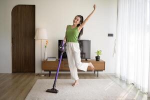 giovane contento donna utilizzando un' vuoto addetto alle pulizie il pavimento nel vivente camera foto