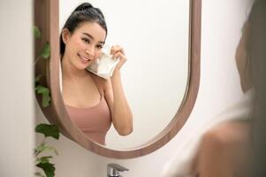 bellissimo asiatico donna è lavaggio e pulizia sua viso foto
