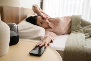 addormentato asiatico donna svolta via allarme su smartphone mentre essere svegliati su nel il mattina foto