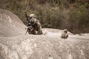 soldati nel camuffare uniformi mirando con loro fucili pronti per fuoco durante militare operazione nel il deserto soldati formazione nel un' militare operazione foto