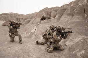 soldati nel camuffare uniformi mirando con loro fucili pronti per fuoco durante militare operazione nel il deserto soldati formazione nel un' militare operazione foto